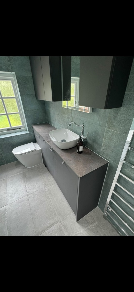 Bathroom vanity with a white counter-top basin, a traditional chrome tap and green-grey stone-effect tiles