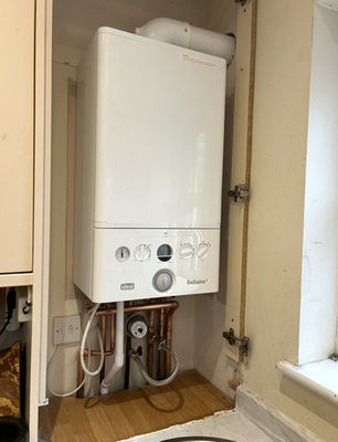 Ideal combi boiler fitted neatly inside a kitchen cupboard with tidy copper pipework